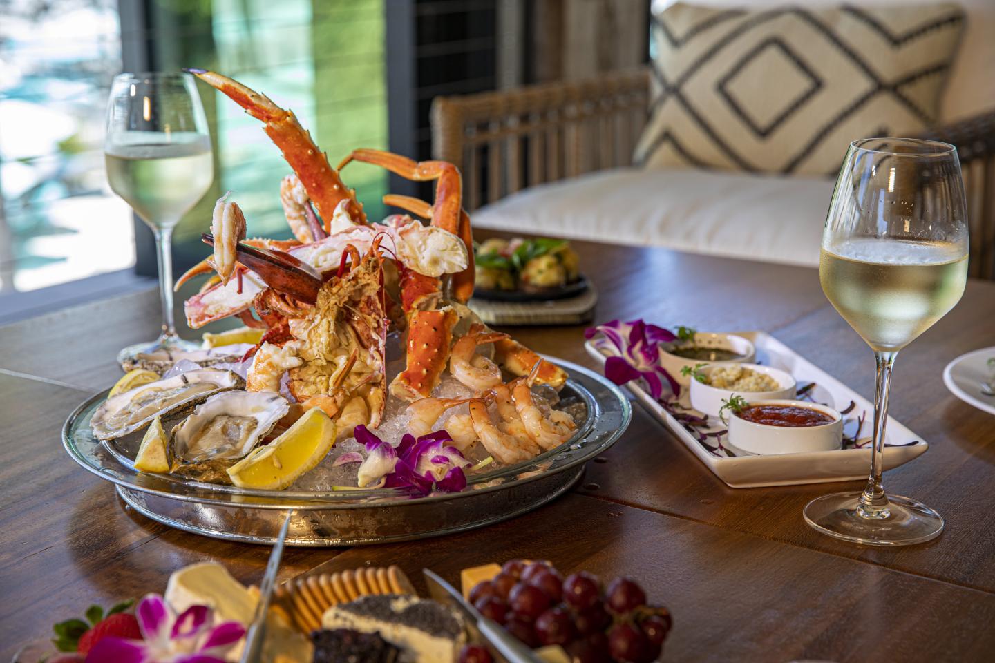 Seafood platter with crab, shrimp, and wine on a wooden table.