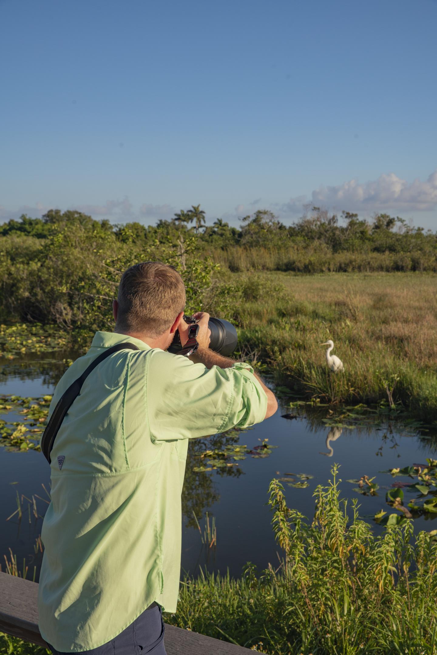 Man photographing a wetland scene with a camera.