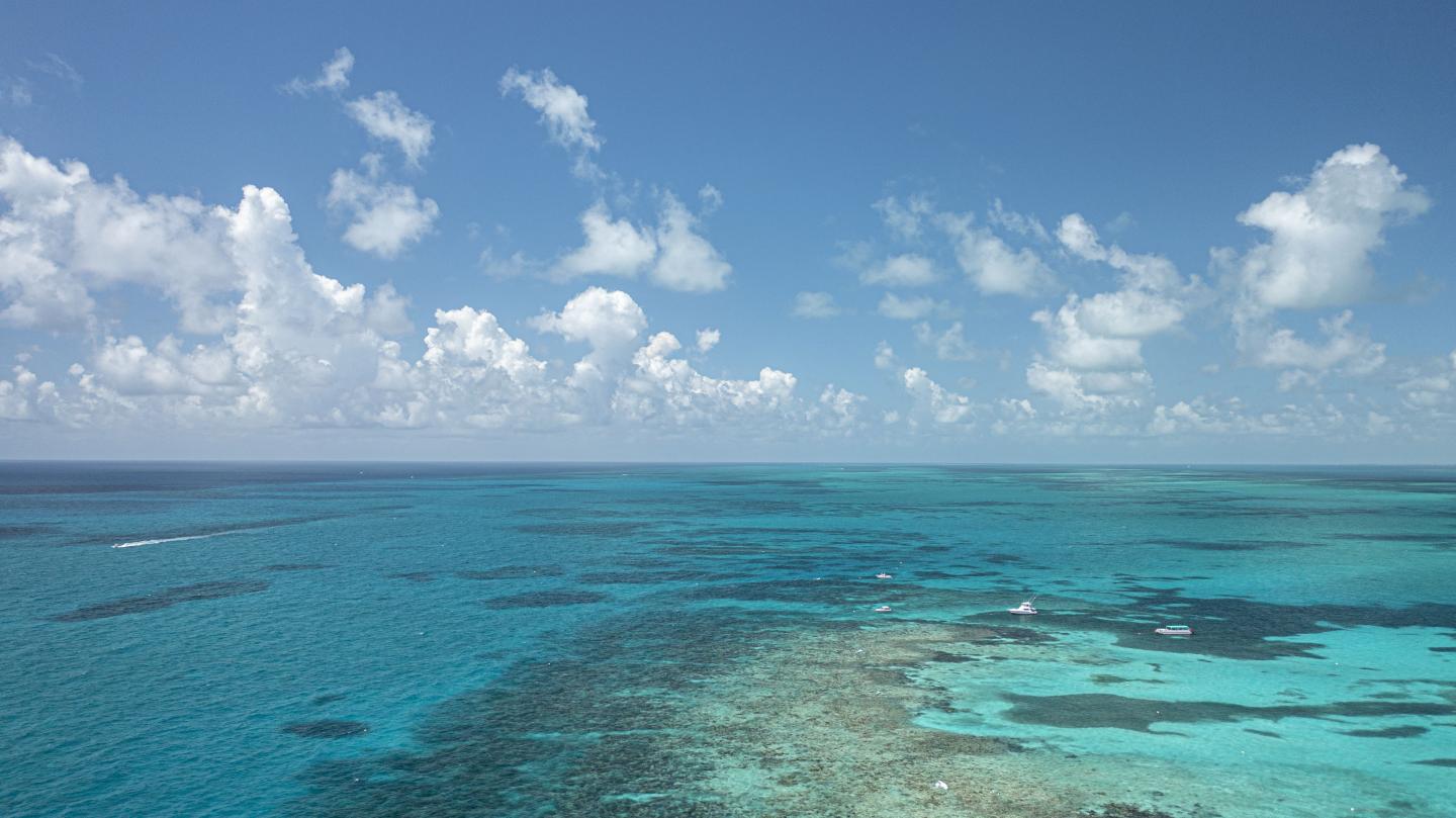 Aerial view of a vibrant blue ocean with scattered clouds.