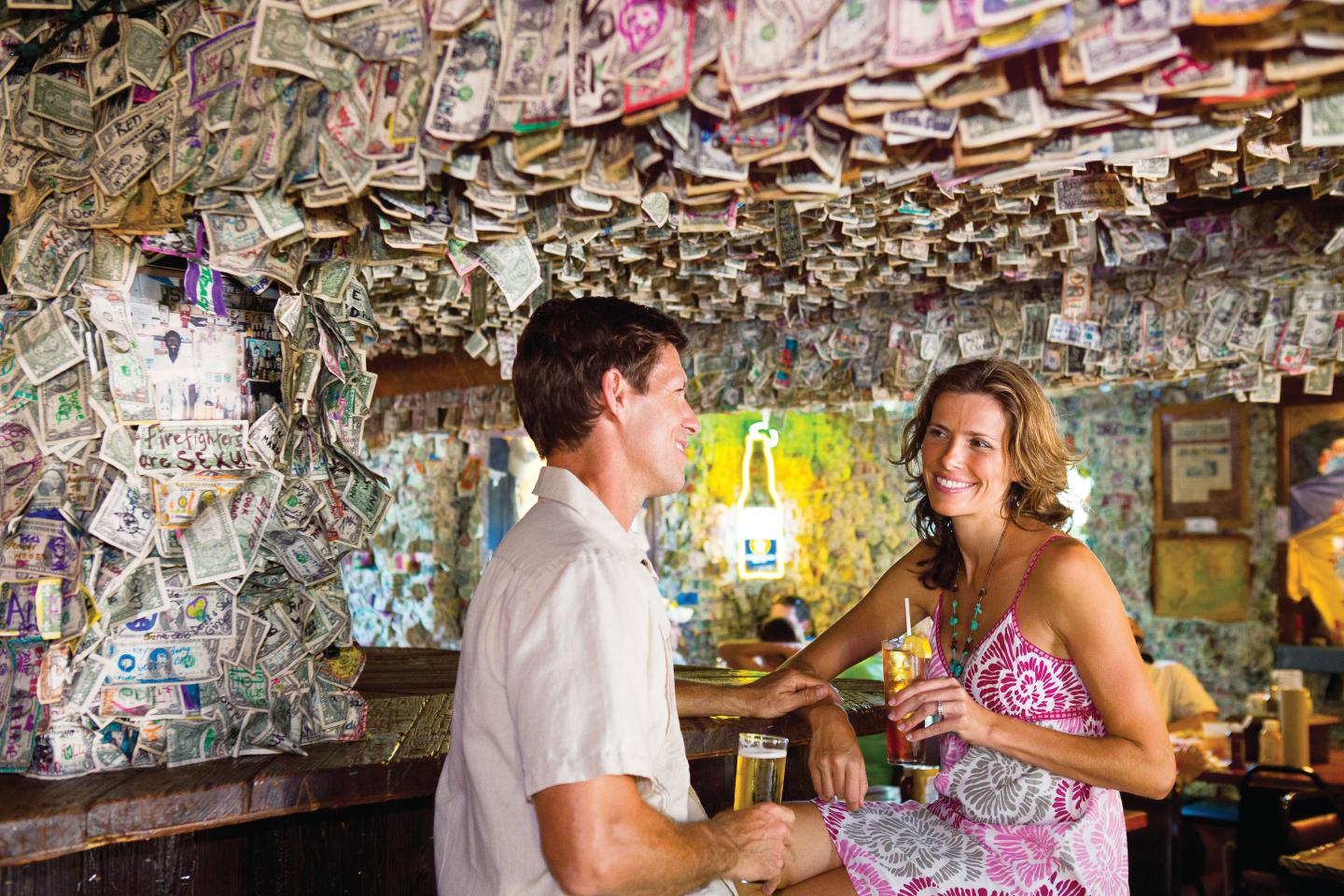 Couple conversing at a bar with walls covered in currency.