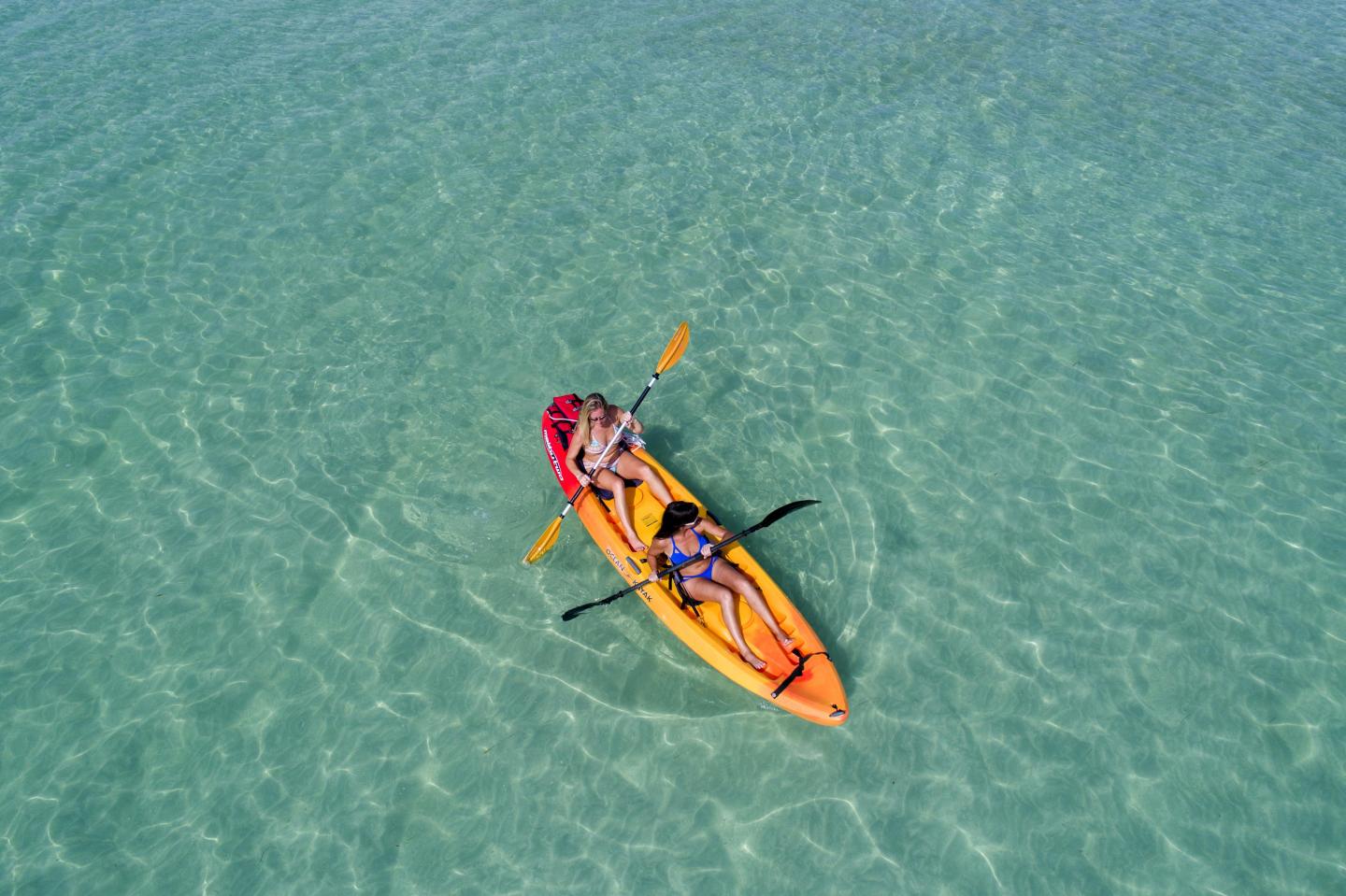 Two people kayaking in clear turquoise water.