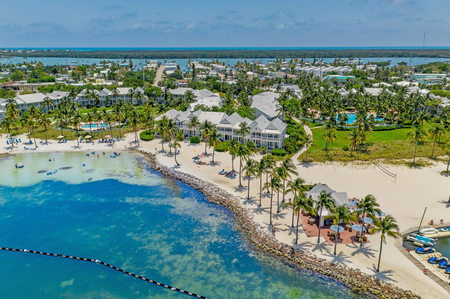 Beachfront resort with palm trees, blue sea, and sandy beaches.