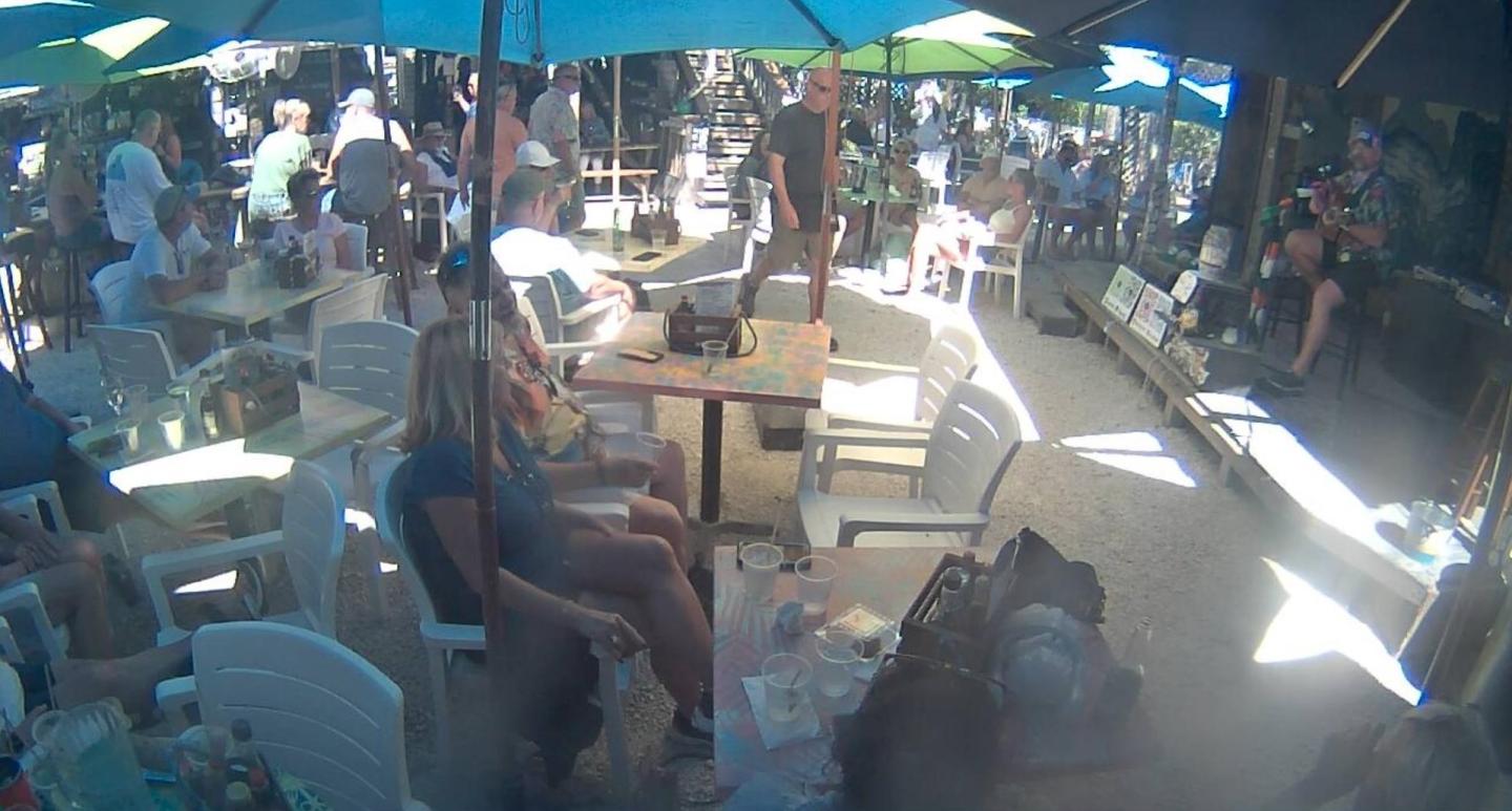 Outdoor café with people sitting under umbrellas. Bright, sunny day.