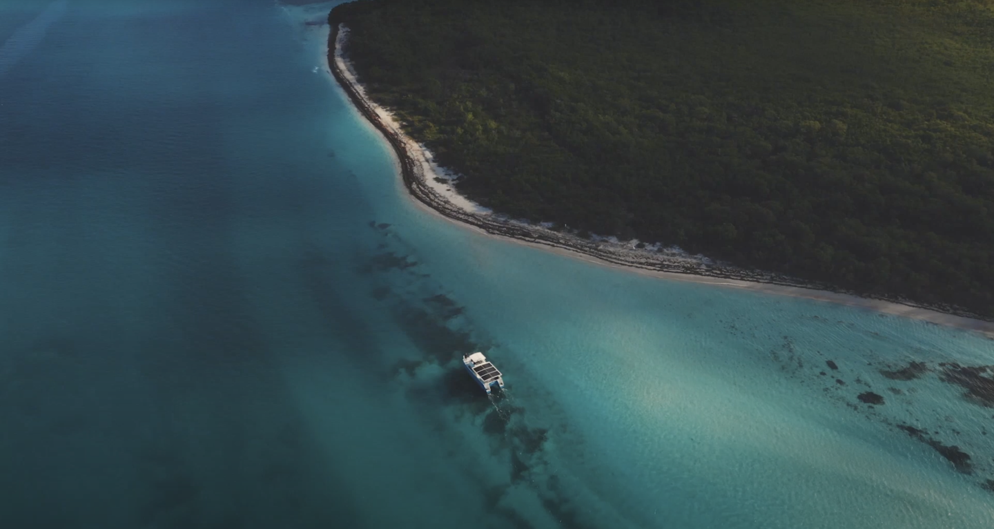 Boat sailing in clear turquoise water near a lush green coastline.