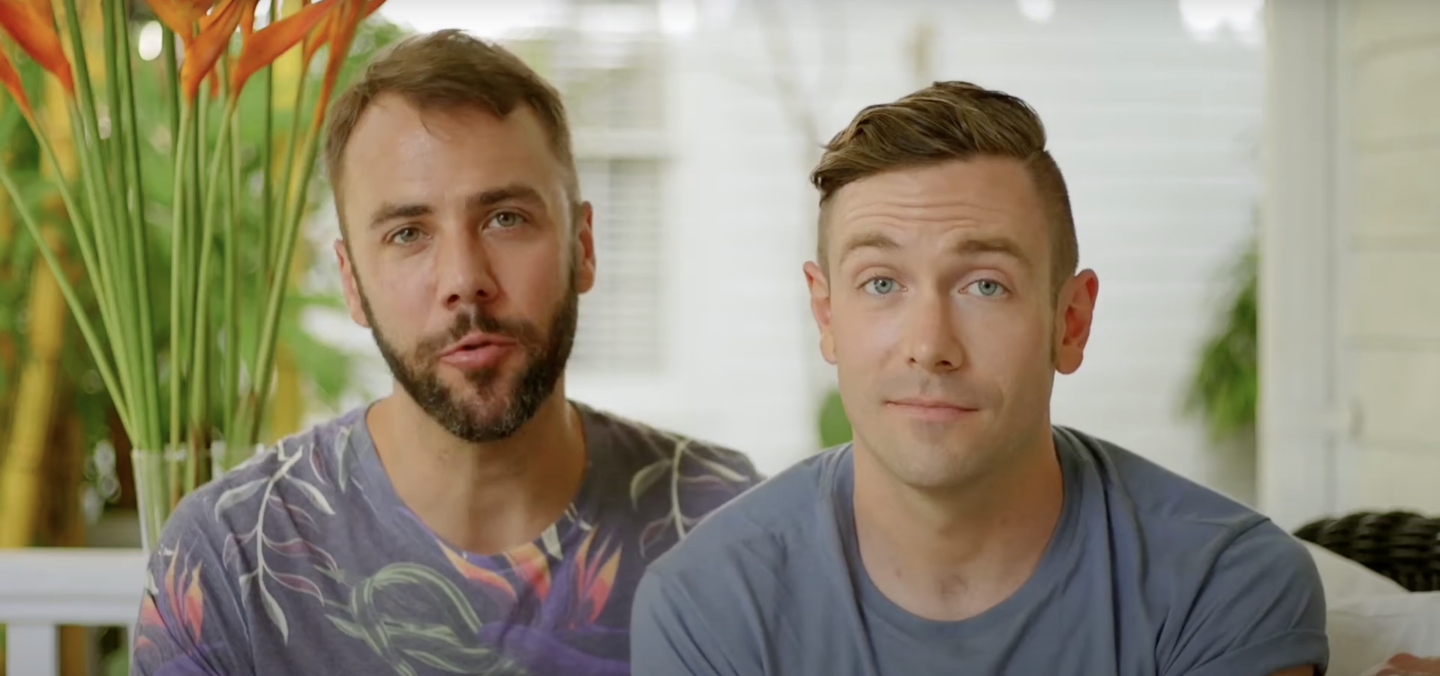 Two people sitting together on a porch, one with a floral shirt, the other with a blue shirt.