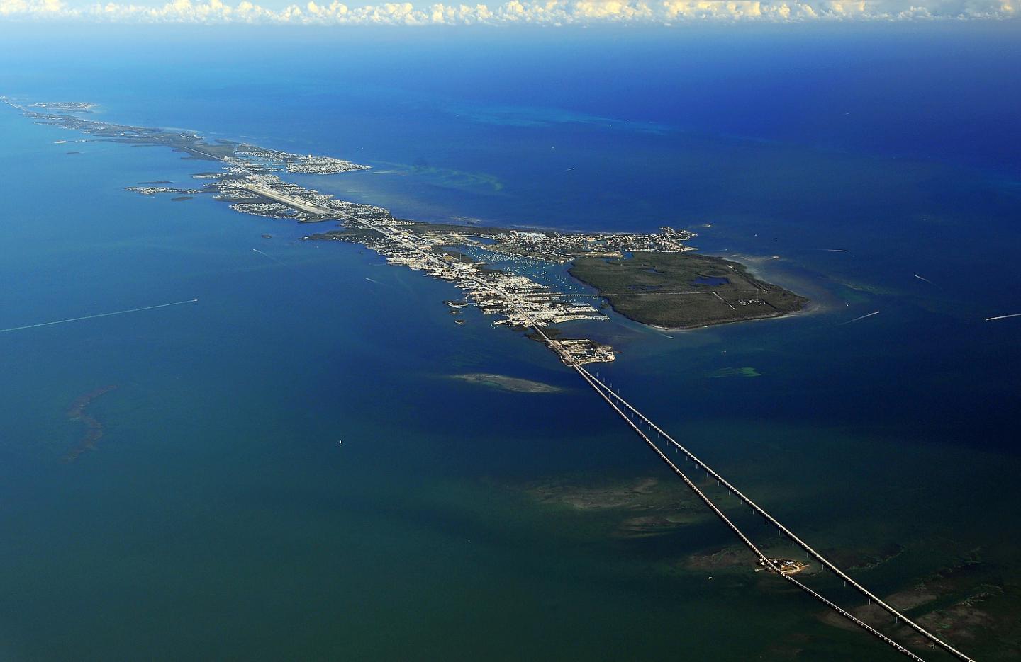Aerial view of a coastal city with a long bridge over blue waters.
