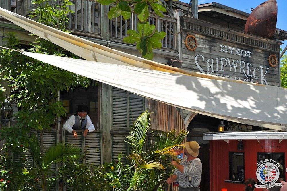Rustic building with sign, man in tropical shirt, sunny day.