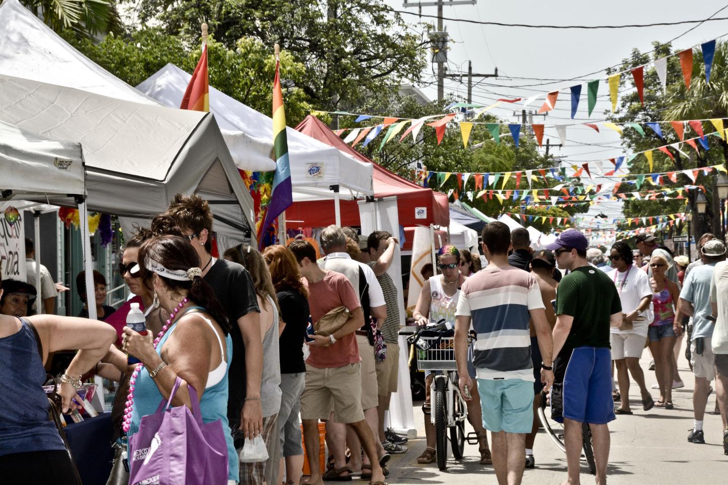 Crowded street festival with colorful tents and flags.