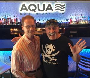 Two men smiling and posing inside a nightclub.