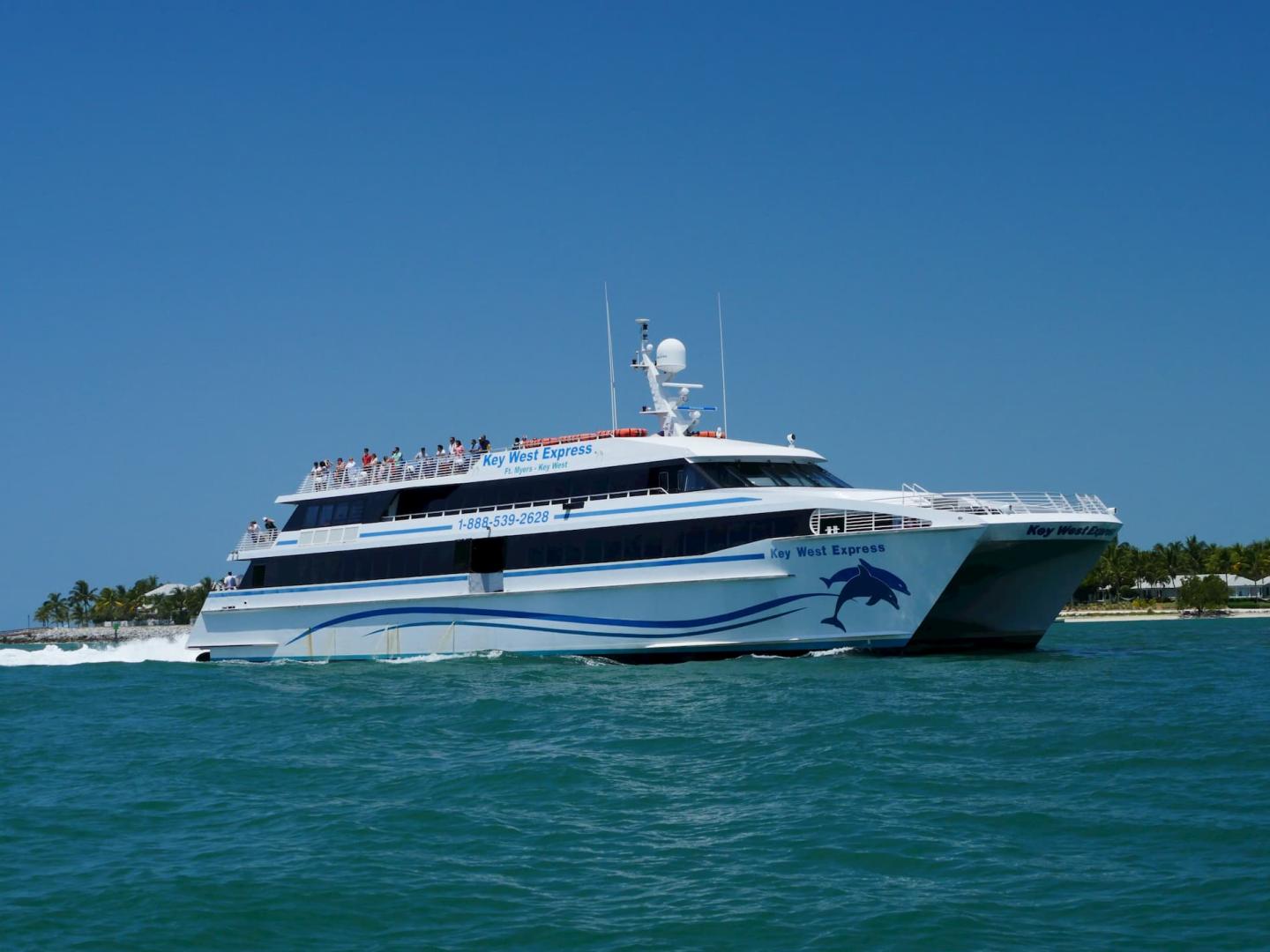 White ferry boat on clear blue water under a sunny sky.