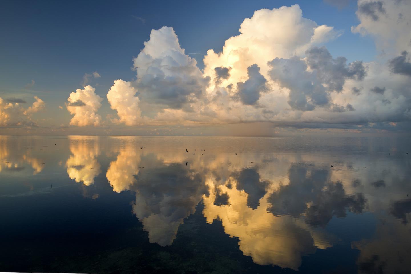 Clouds reflecting on calm water at sunset.