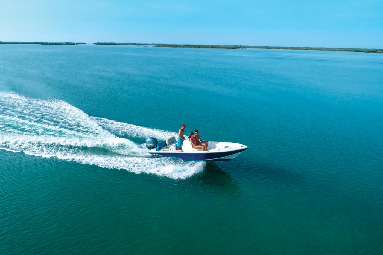 Speedboat glides across calm blue water under clear sky.