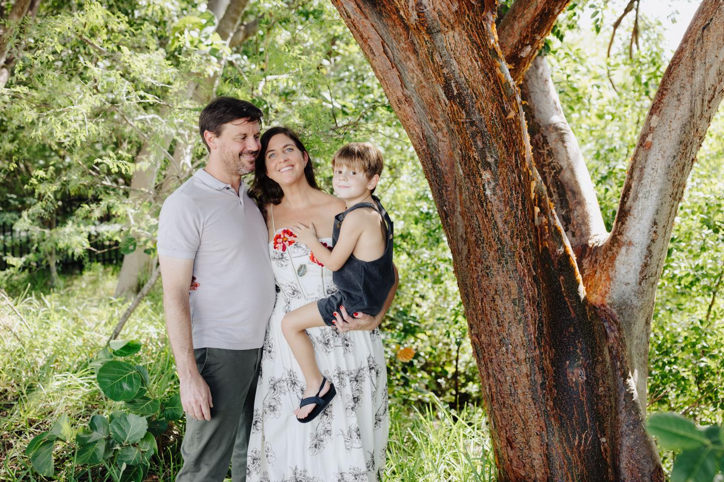 Family smiling under a tree in a lush garden.
