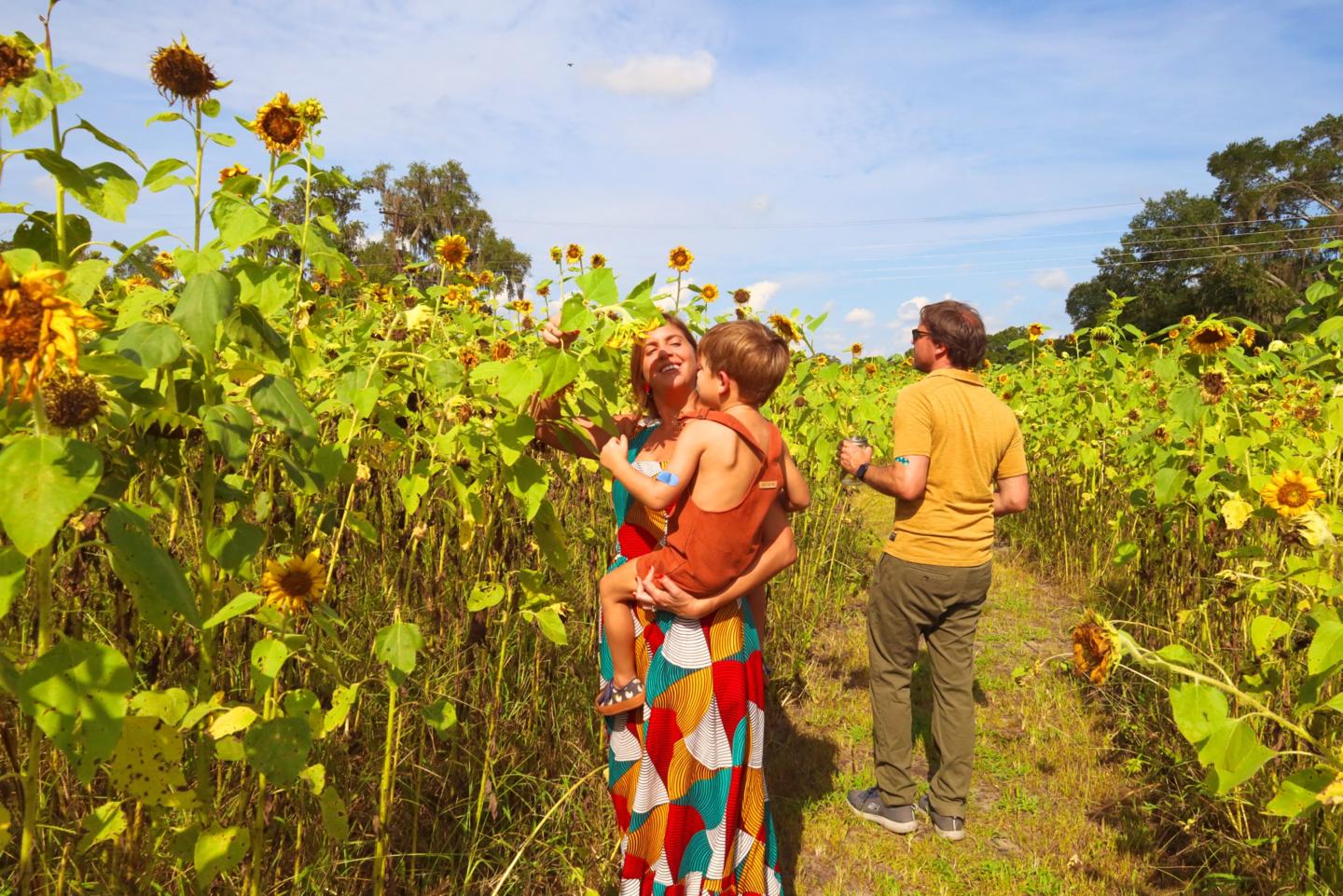 Family enjoying a sunny day in a sunflower field.