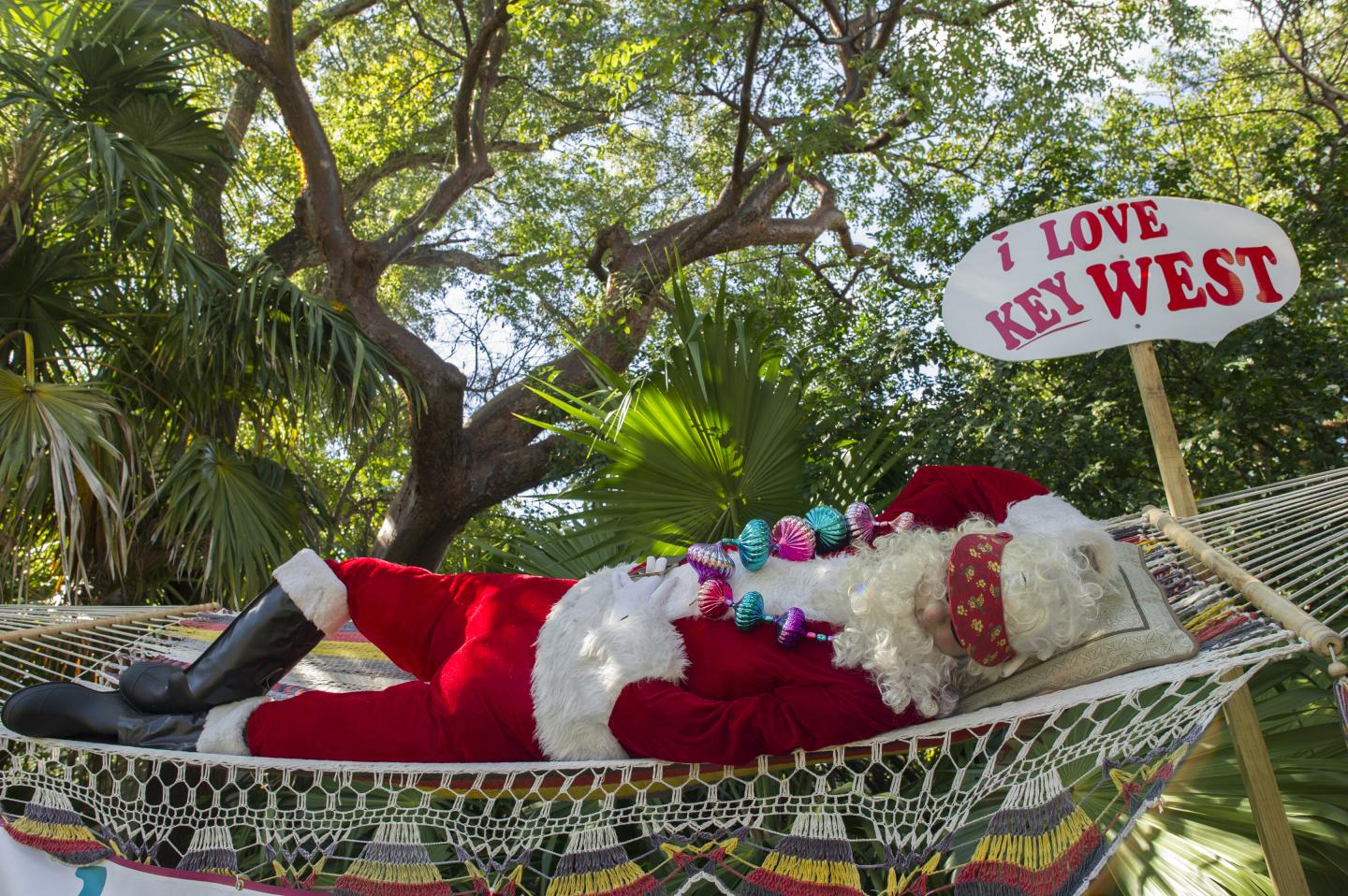 Santa Claus relaxing on a hammock in a tropical setting.