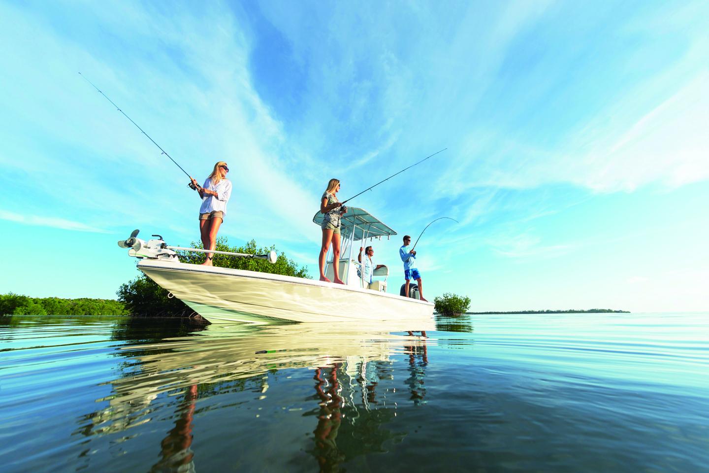Fishing group on a boat in calm, reflective water under a bright blue sky.