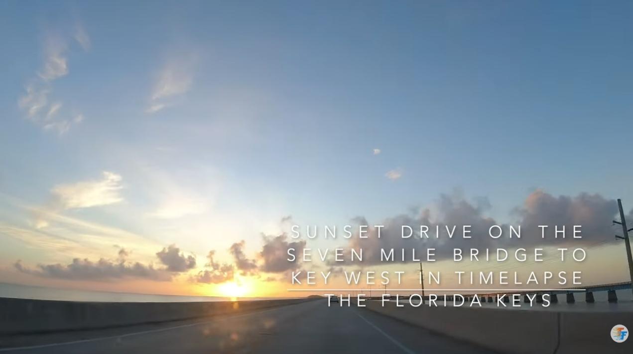 Sunset view from a car on a bridge, with a blue sky and scattered clouds.