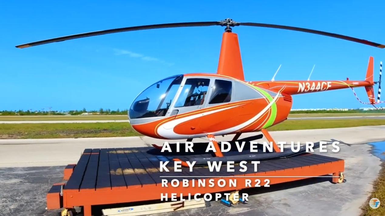 Red helicopter parked on a platform against a clear blue sky.