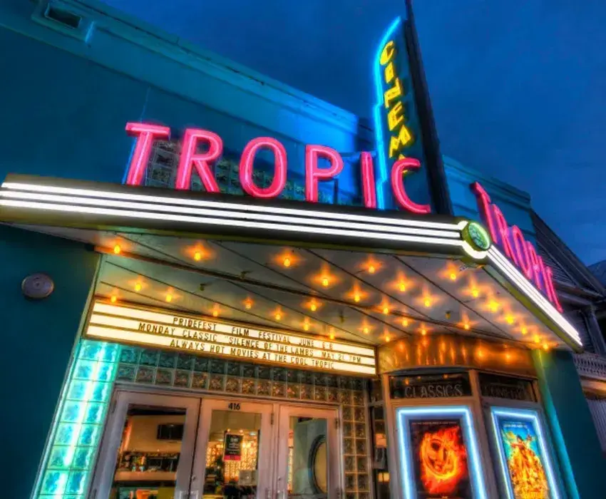 Tropic Cinema entrance lit with neon lights against dusk sky.