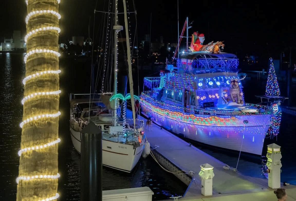 Festively lit boat at night with colorful lights and holiday decor.