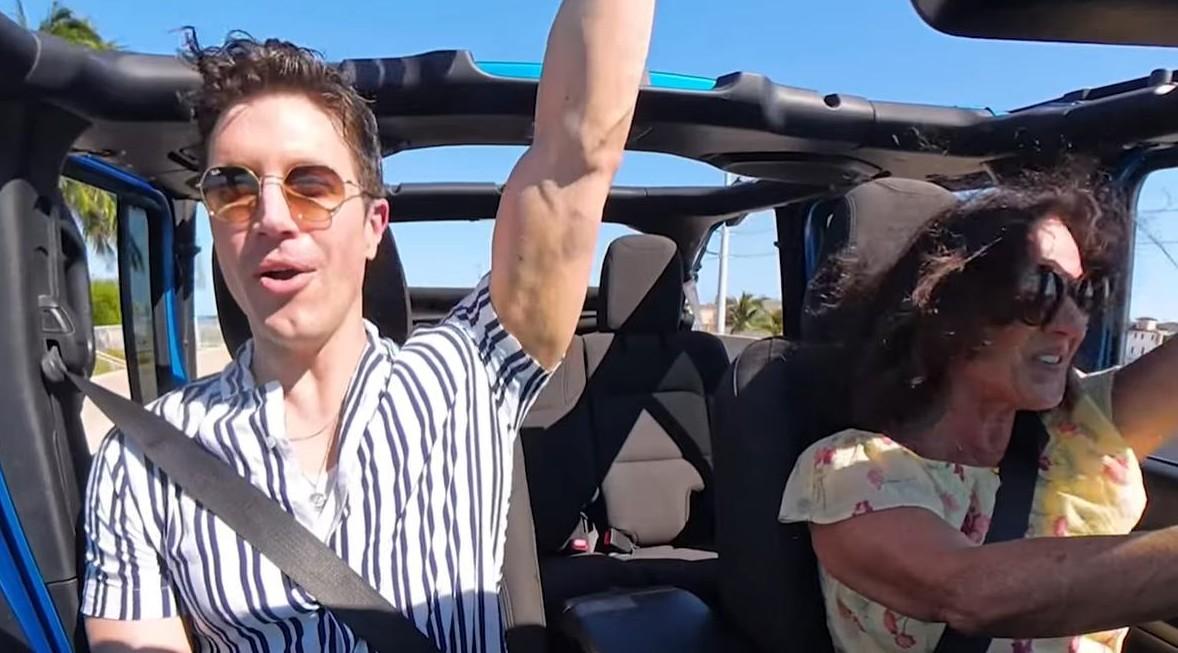 Two people in a convertible, smiling and enjoying a sunny drive.