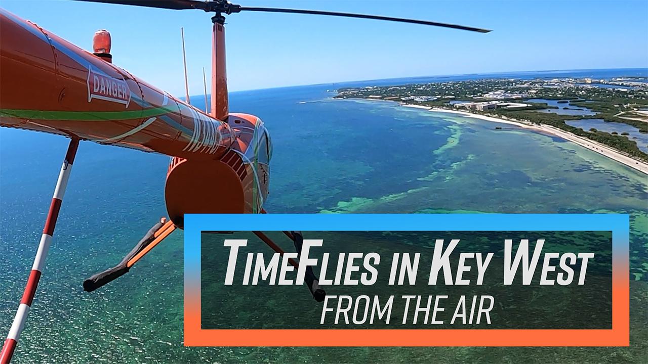 Helicopter over Key West coastline with clear blue sea.