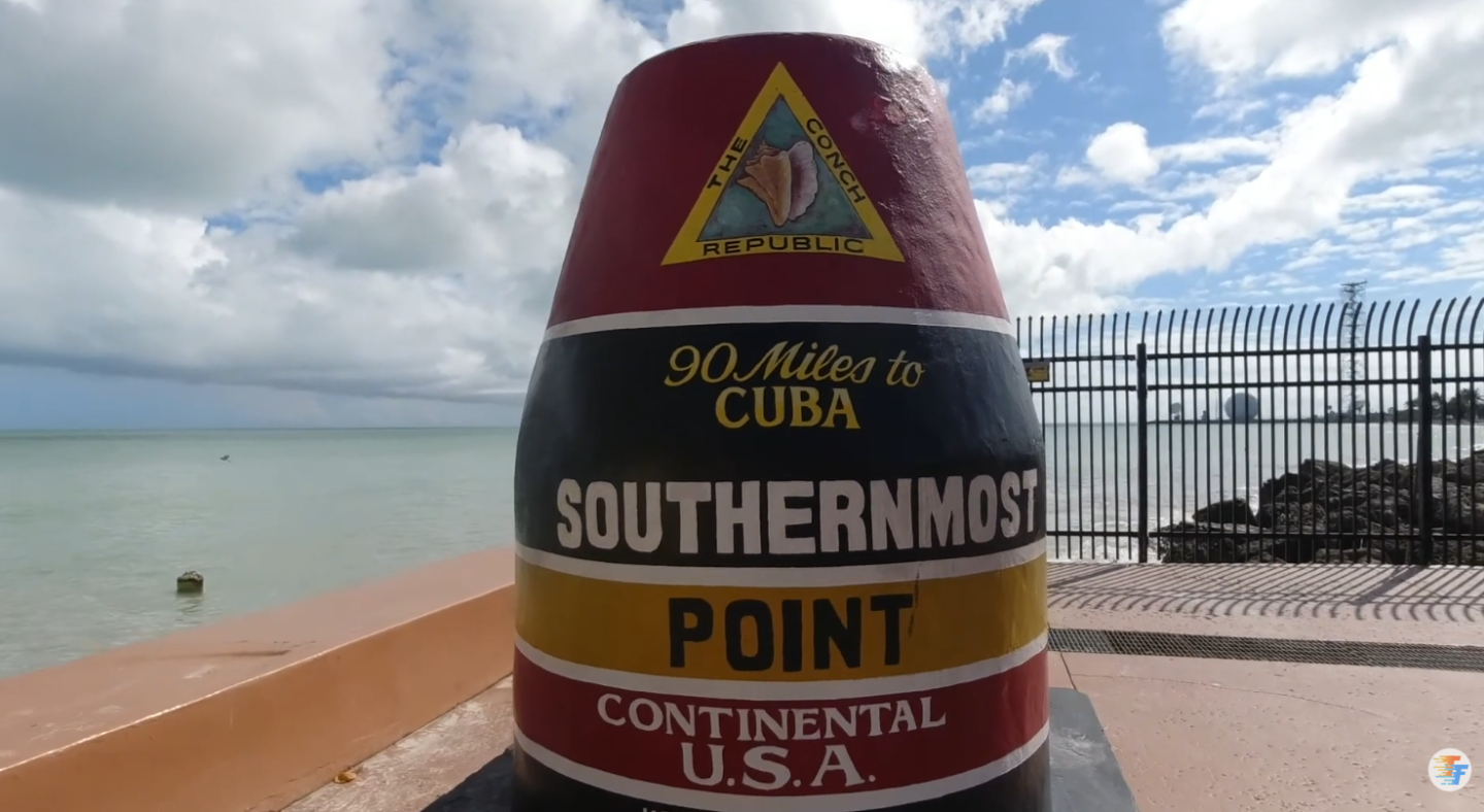 Colorful Southernmost Point buoy in Key West with ocean in the background.