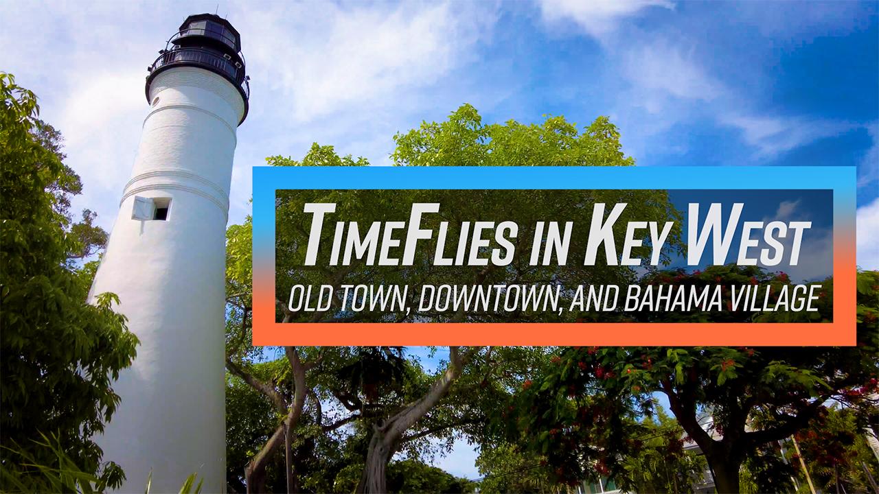 White lighthouse and trees under a blue sky.