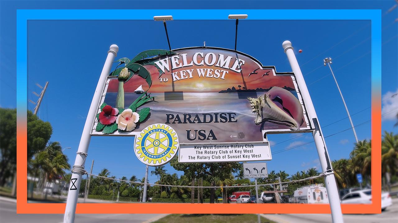 Welcome sign for Key West, with tropical imagery against a blue sky.