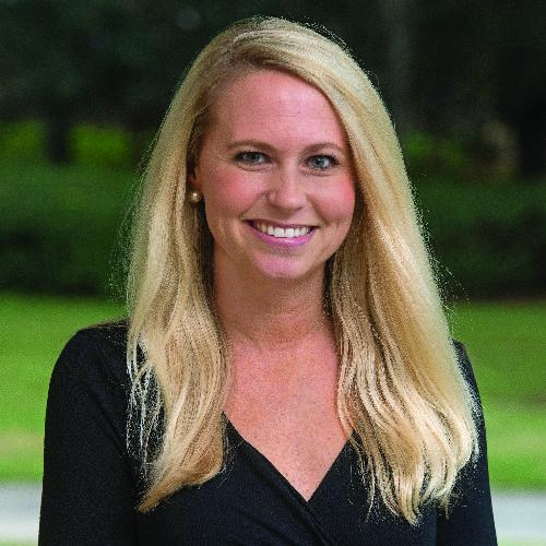Smiling woman with long blonde hair and a black top outdoors.
