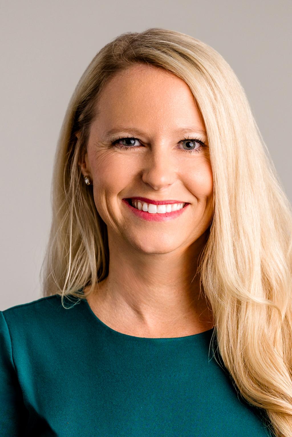 Smiling woman with long blond hair in a green top.