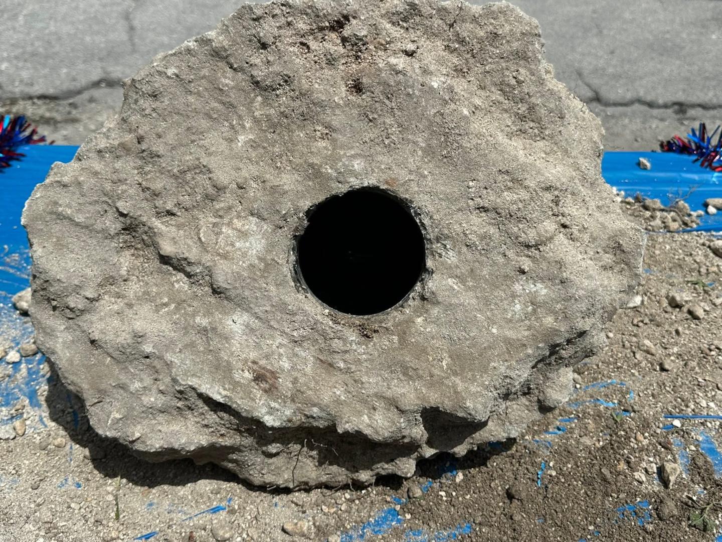 Rock with a large circular hole in the center, set on a blue surface.