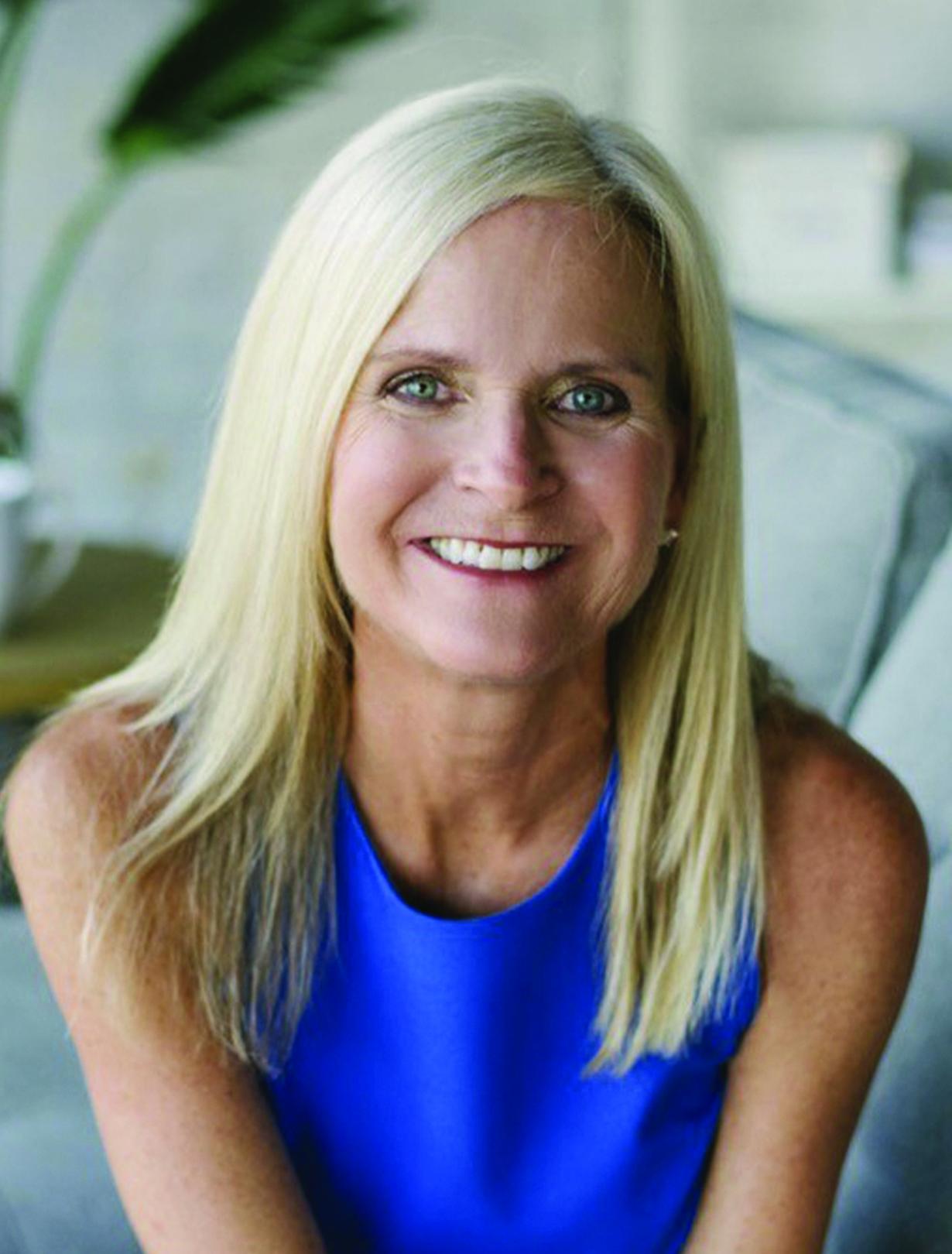 Smiling woman with long blonde hair in a blue top.