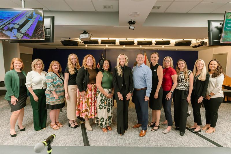Group of people smiling in a conference room, standing in a line.