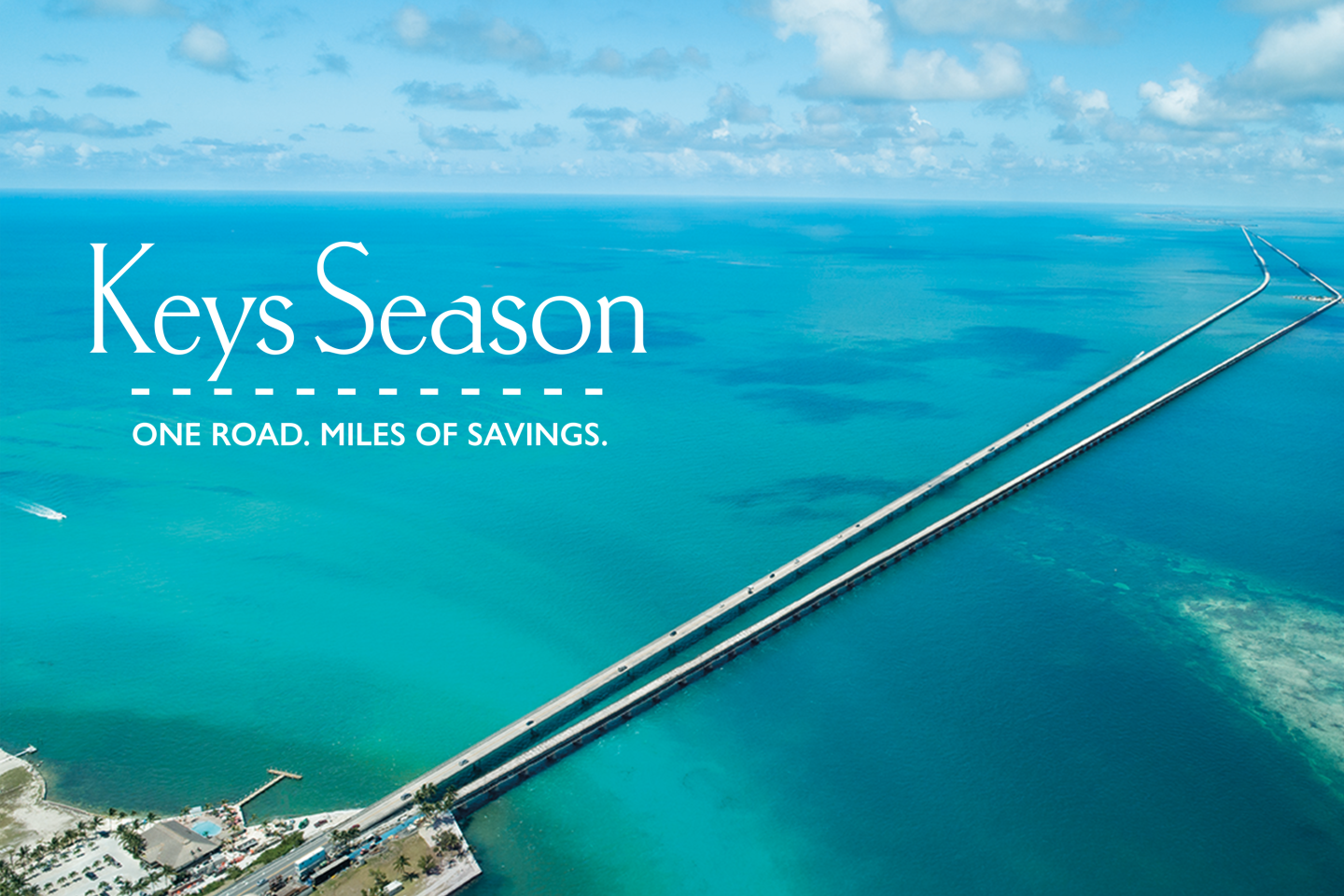 Long bridge stretches over turquoise ocean under a blue sky.