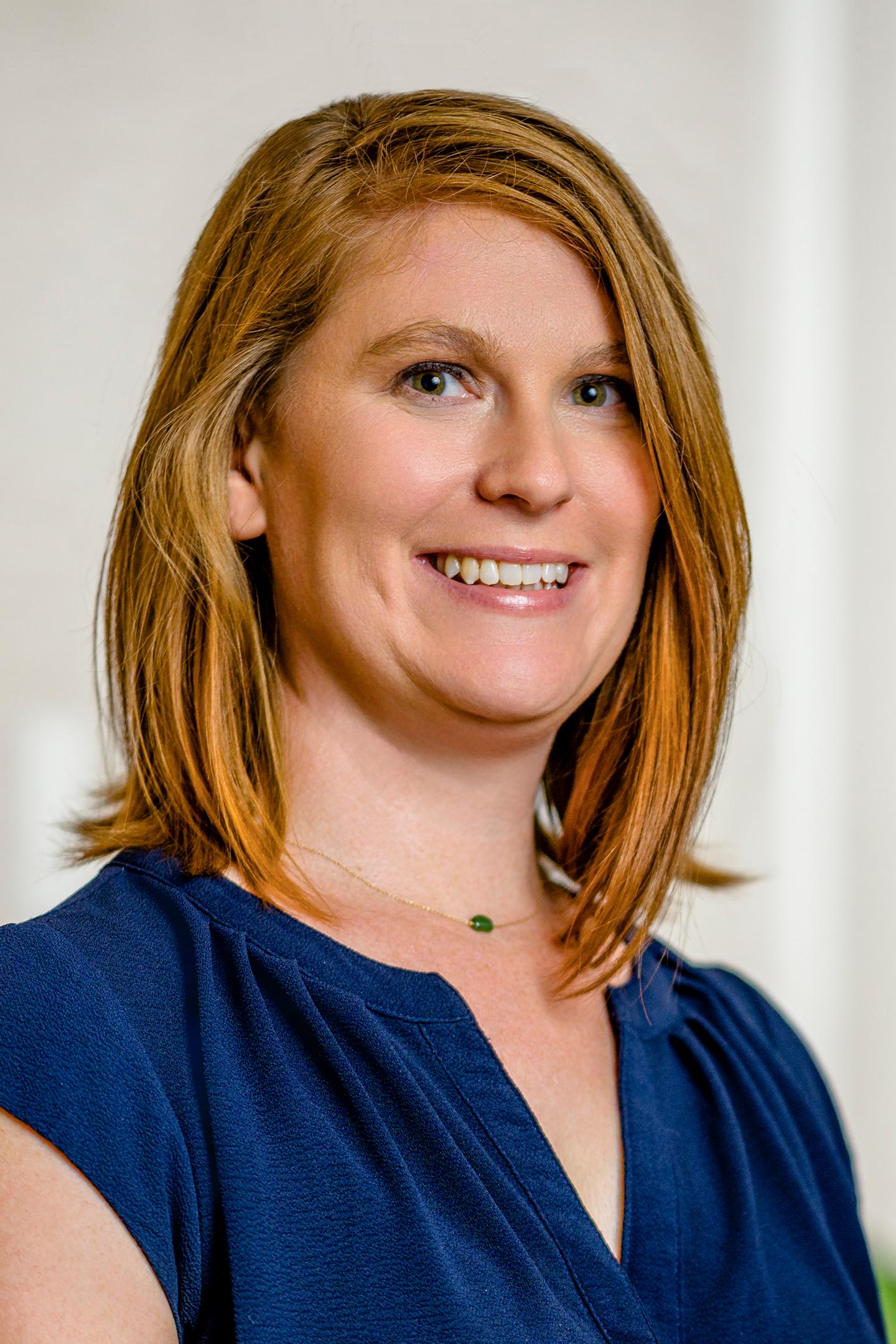 Smiling person with shoulder-length hair, wearing a blue blouse.