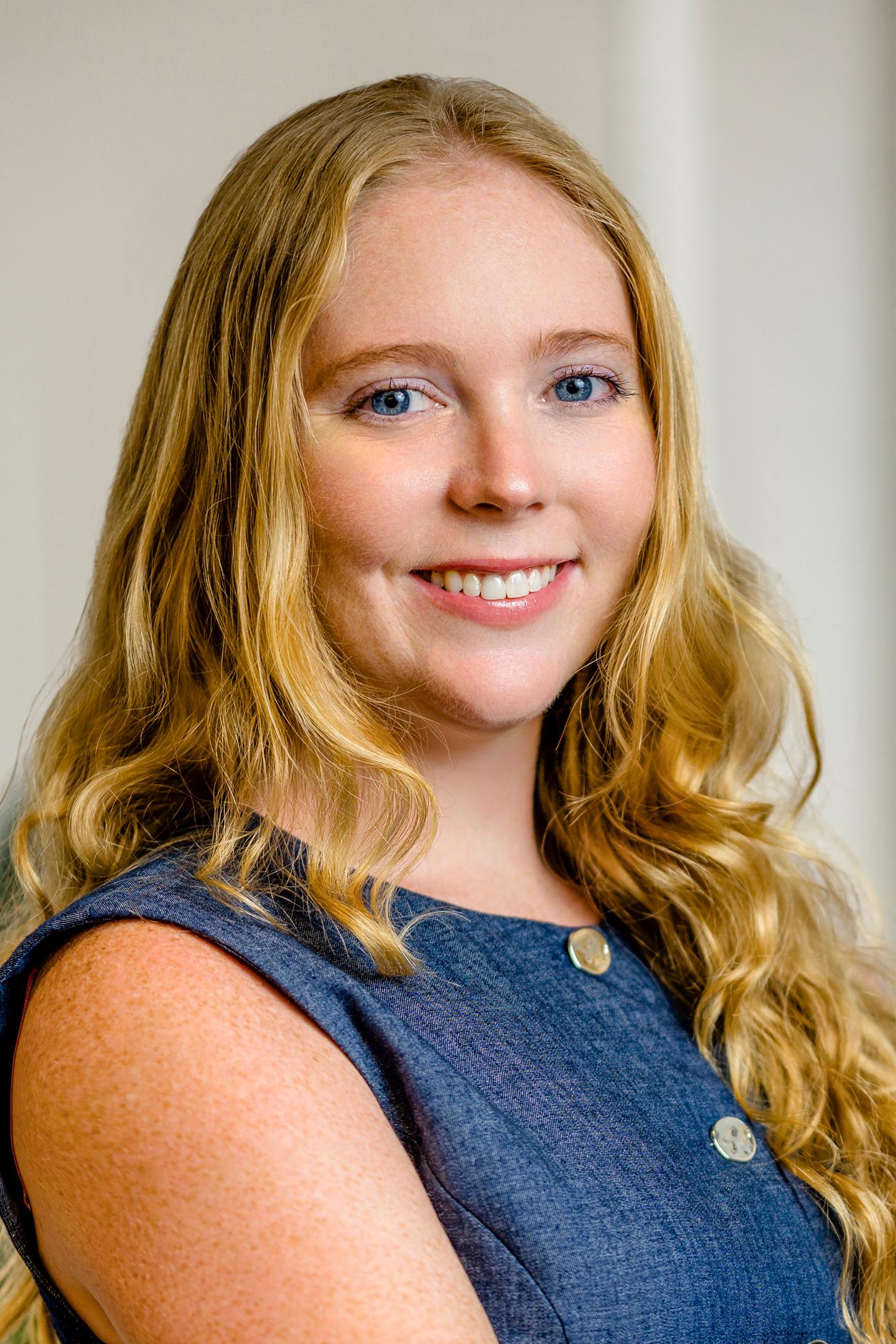 Smiling woman with long blonde hair in a blue dress.