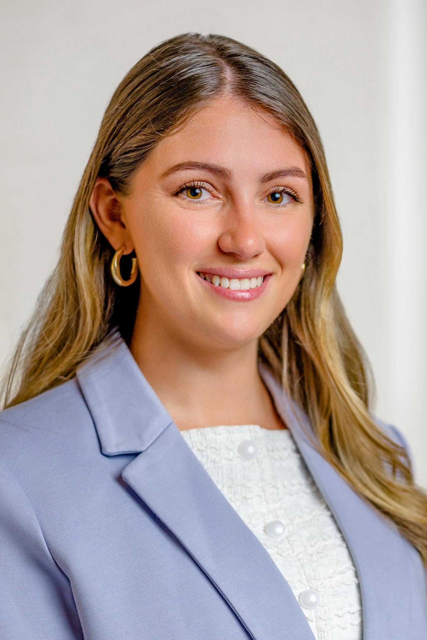 Smiling woman in a light blue blazer with long, blonde hair.