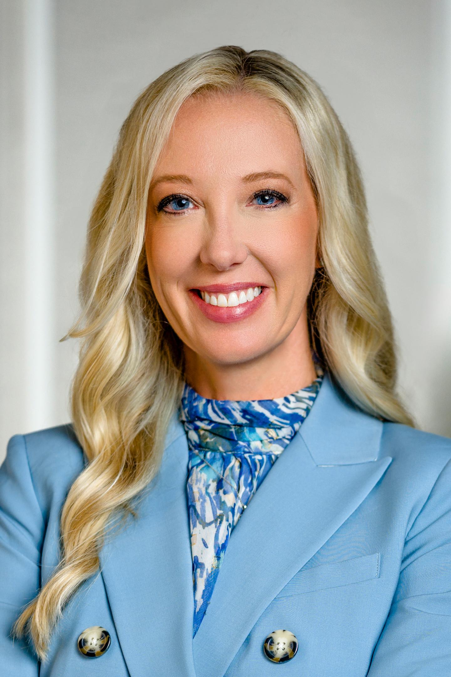 Smiling woman with long blonde hair in a blue blazer.