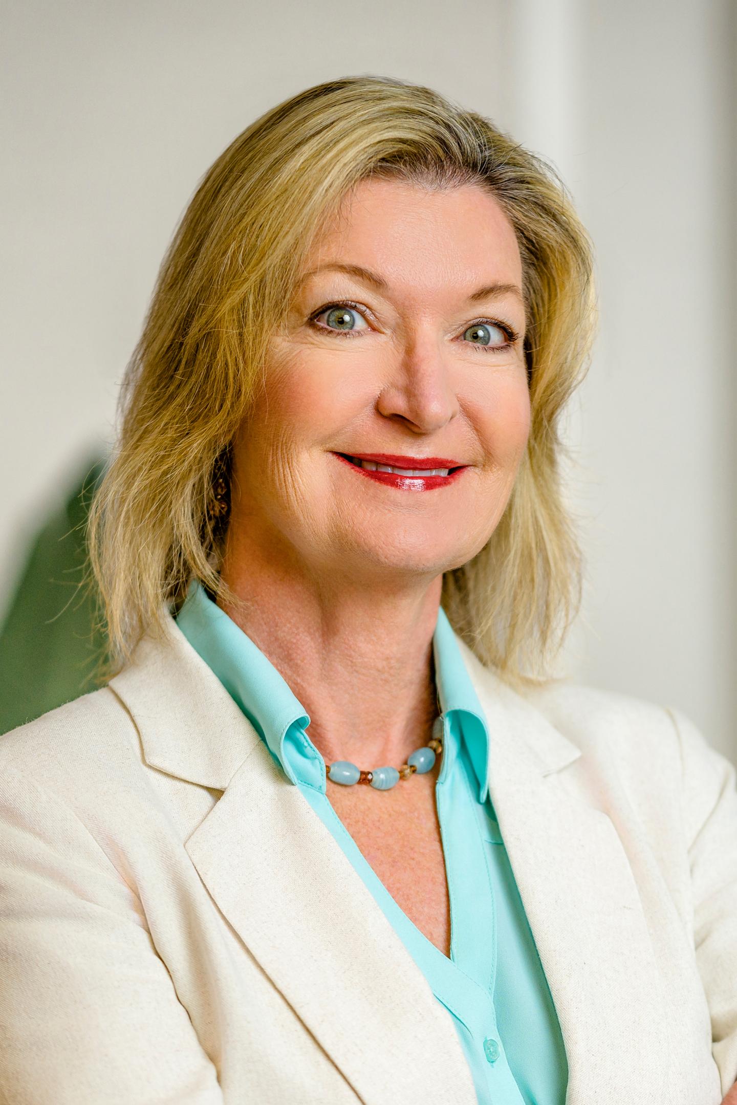 Smiling woman with blonde hair in a white blazer.