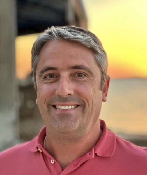 Smiling man outdoors at sunset.