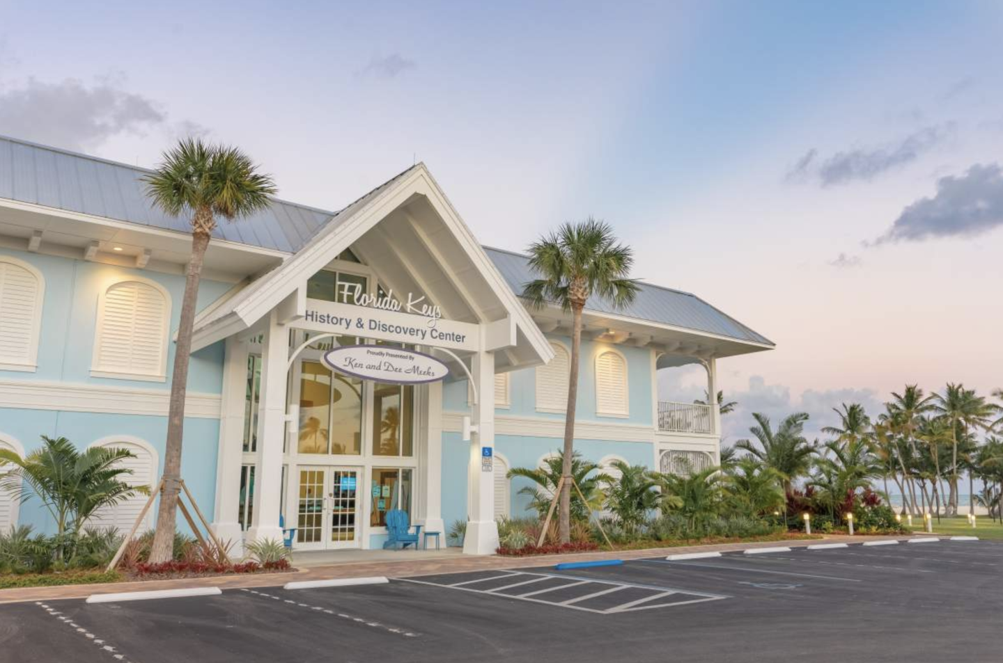 Tropical building with palm trees and pastel colors at sunset.