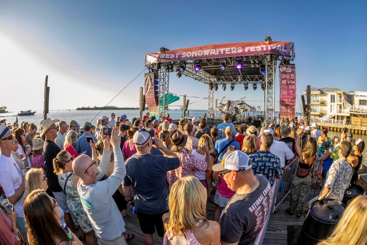 Crowd enjoying a sunny outdoor music festival by the waterfront.