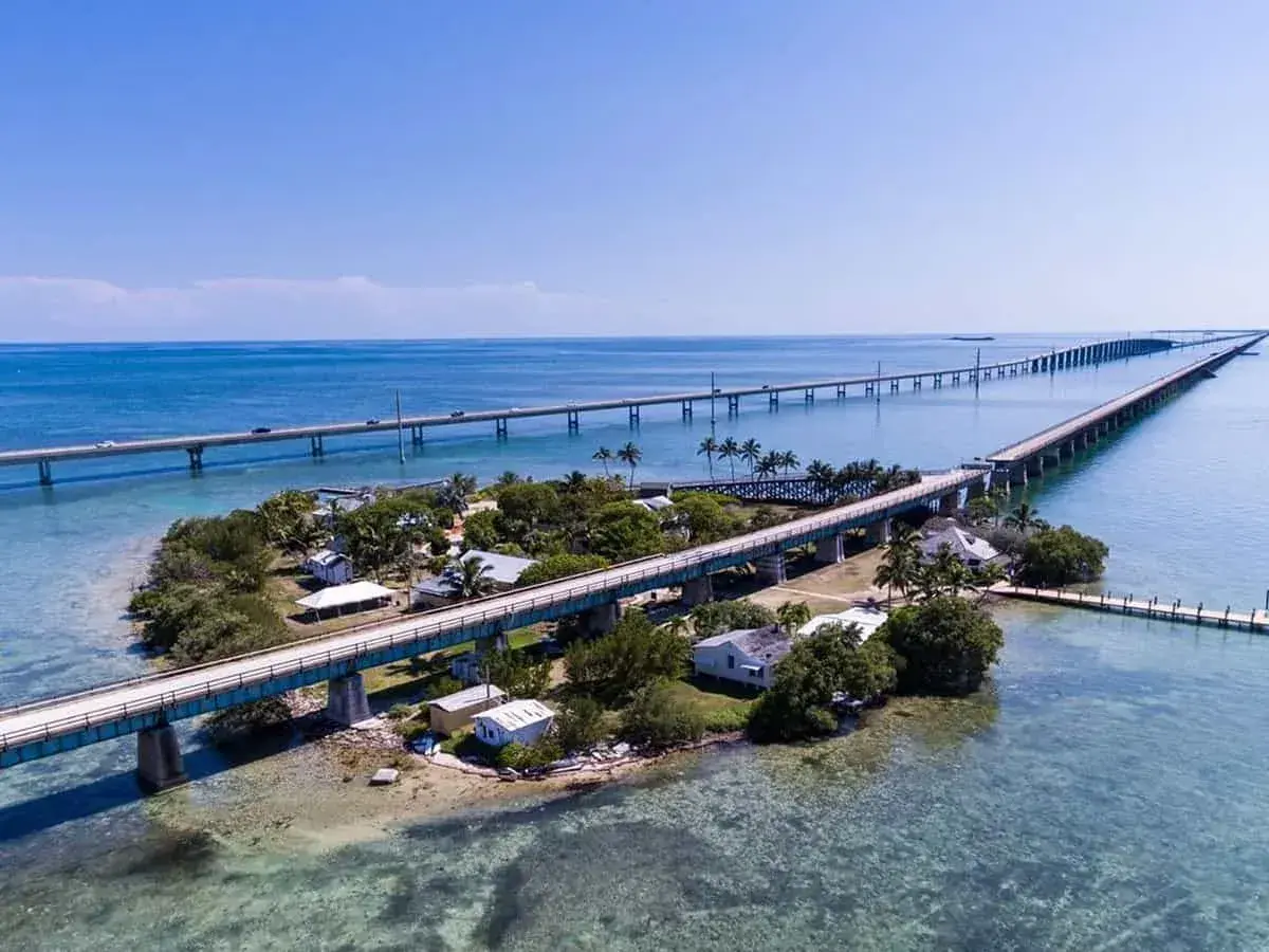 Causeway bridge over turquoise sea, connecting small islands.