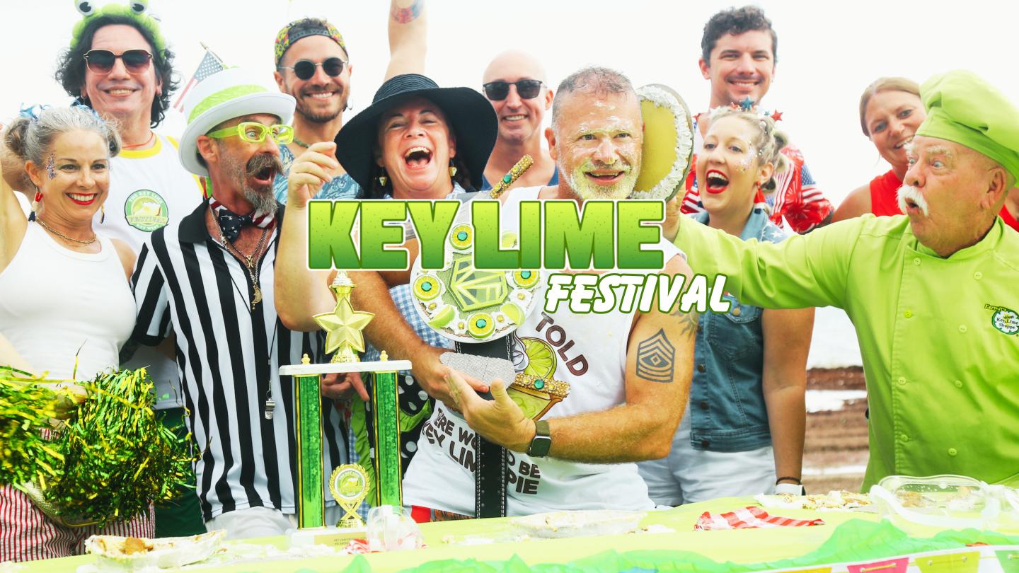 People celebrating at a festival holding a large trophy and smiling.