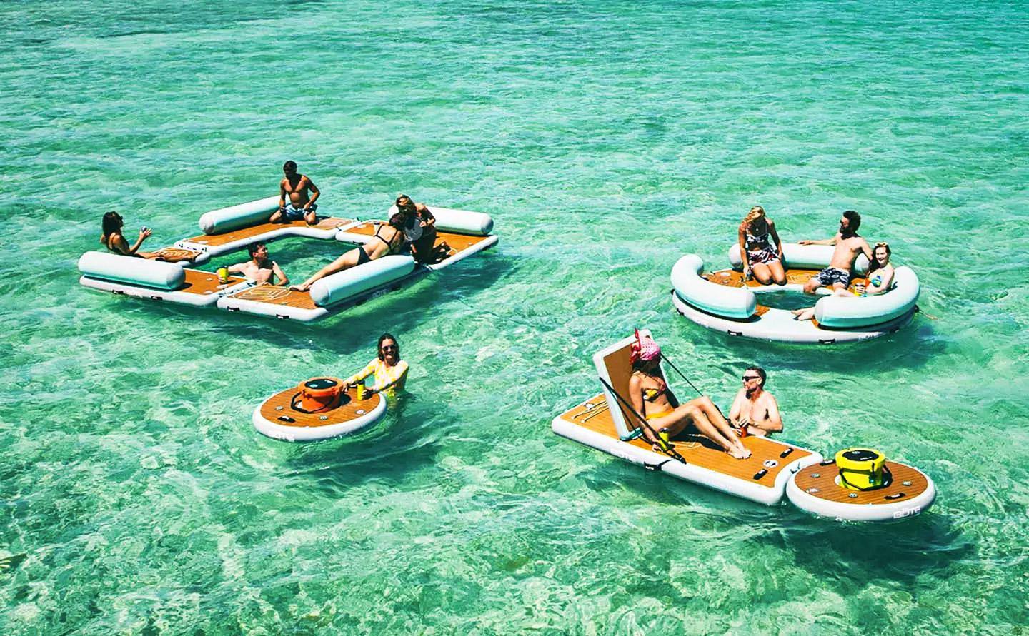 People relaxing on inflatable platforms in clear turquoise water.