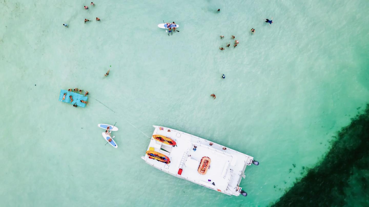 Aerial view of boats and swimmers in turquoise water.
