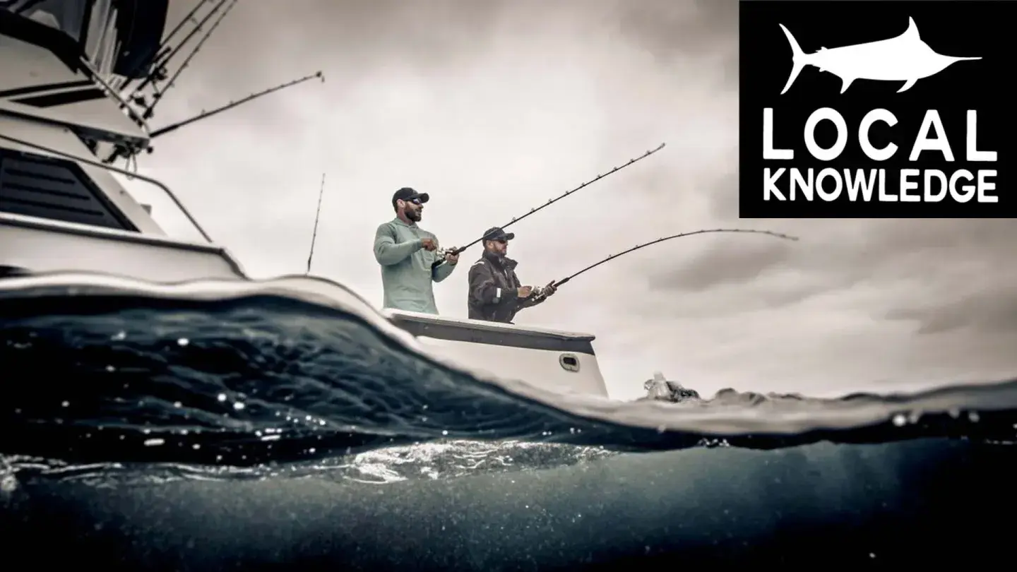 Two anglers fishing from a boat under cloudy skies, with a logo showing a fish silhouette.