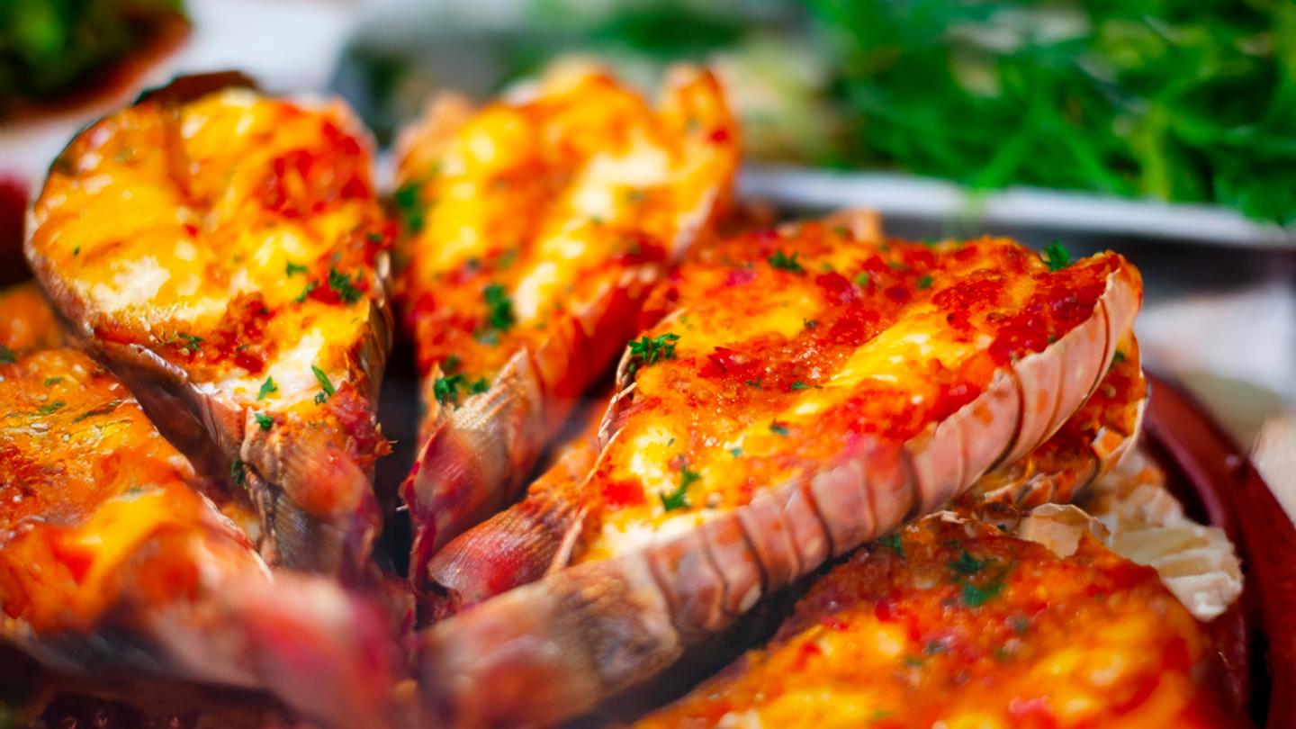 Grilled lobster tails garnished with herbs, served on a ceramic platter.