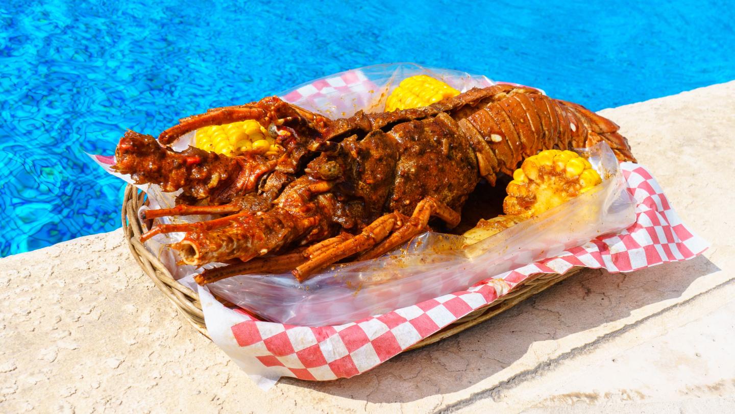Grilled lobster with corn by a poolside.